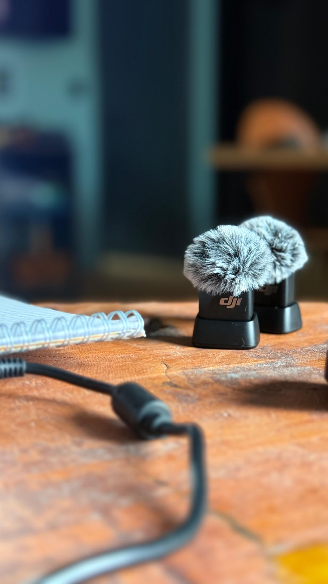 Deux micros-cravates posés sur une table en bois avec un carnet de notes