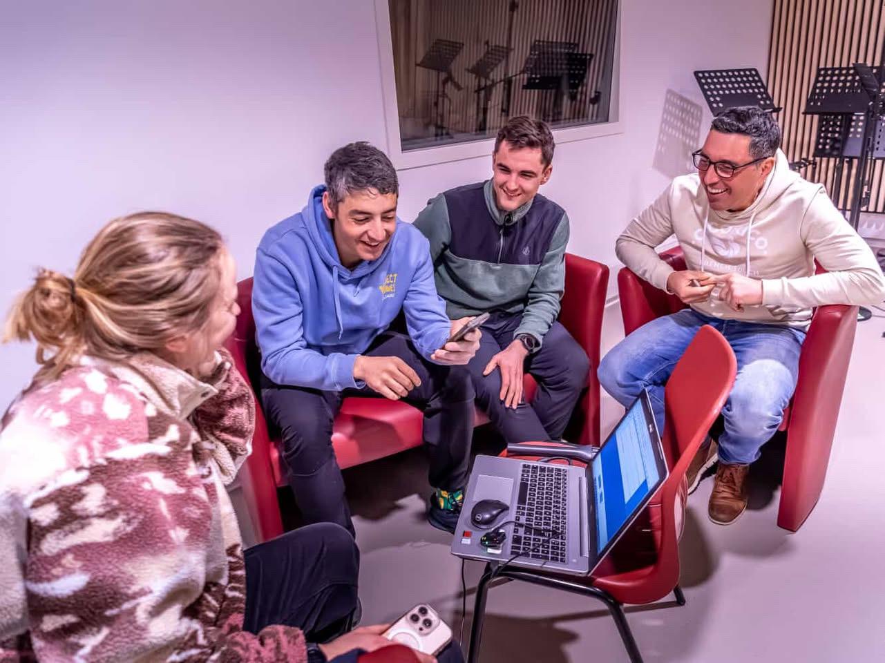 Enregistrement en studio avec quatre invités souriants autour d'un ordinateur